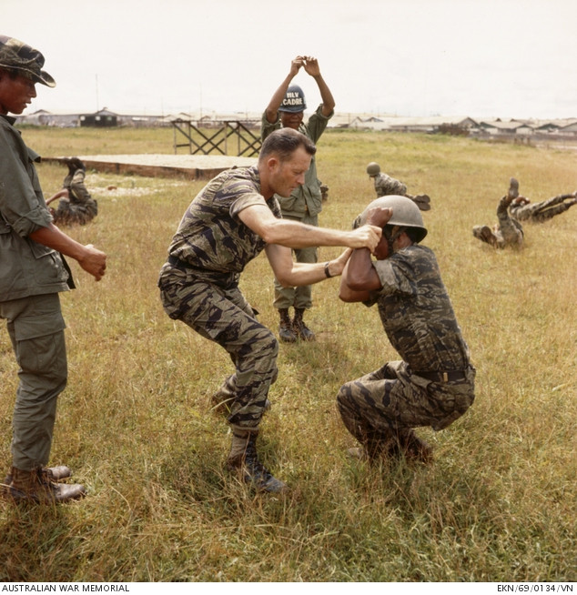 Australian Army Training Team advisor in tiger stripe instructing Montagnards, 1969