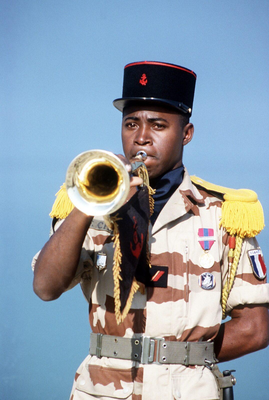French Marine Troops bugler in a Daguet desert camouflage uniform and a black kepi with a red anchor badge at a beach reopening ceremony in Kuwait City, Kuwait, 30 March 1991