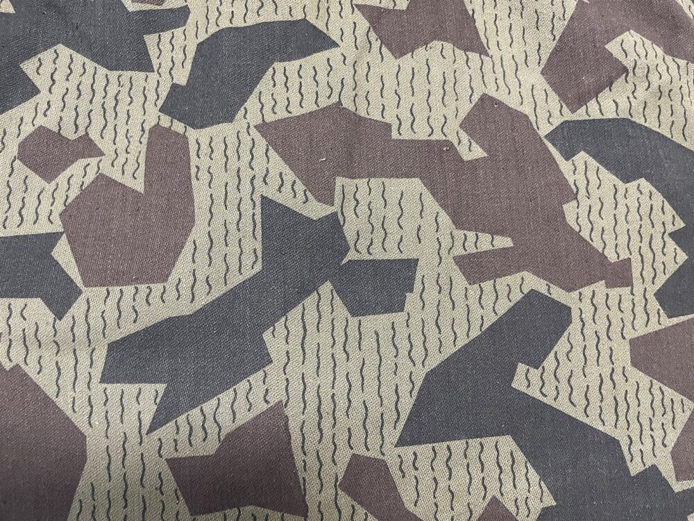 Close-up of Bulgarian splinter printed cloth: brown and very dark angular shapes crossed by thin wavy streak lines on a pale sandy ground