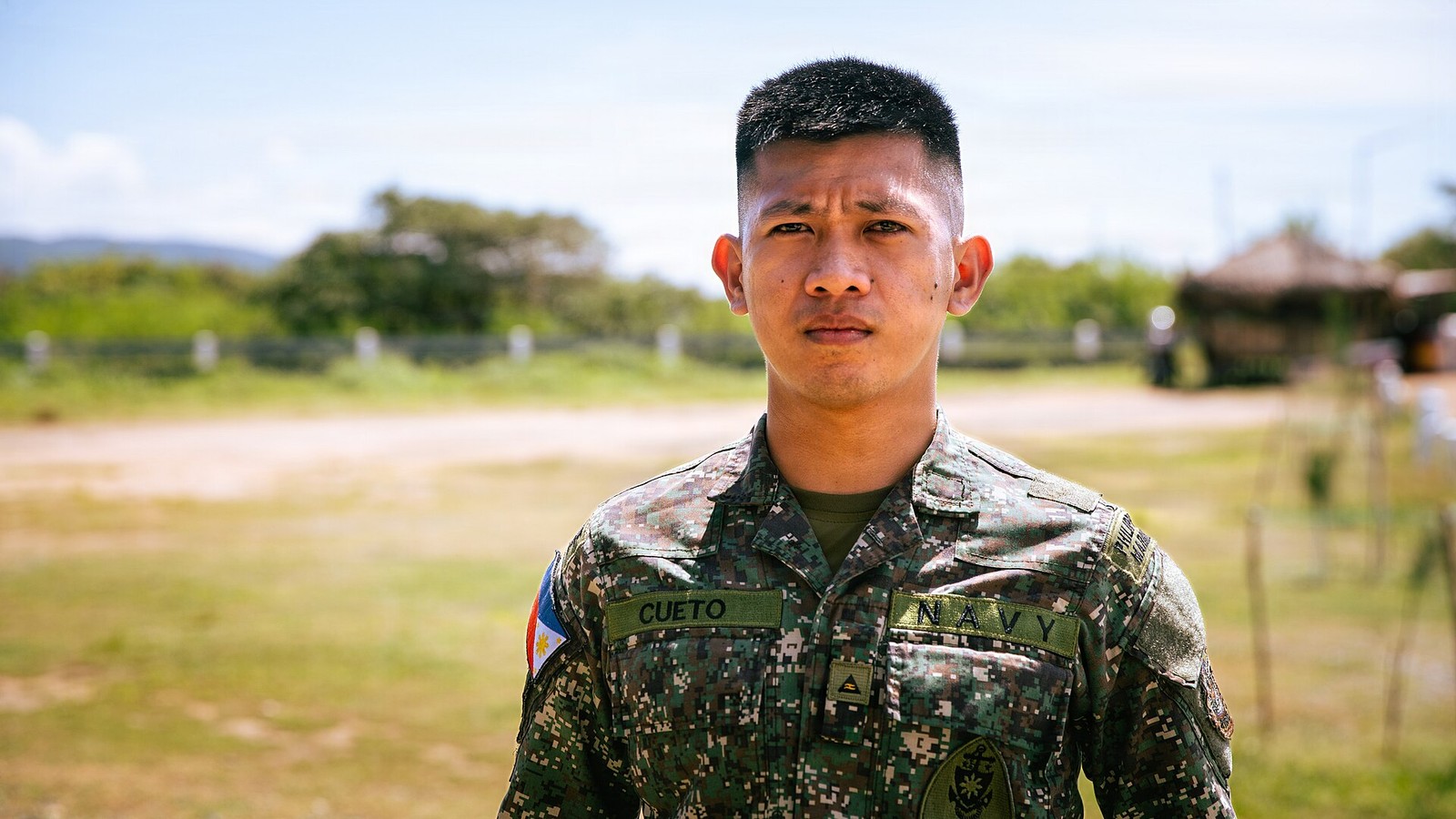 Portrait of a Philippine Marine Corps officer wearing a green square-block digital camouflage uniform, with the Philippine flag patch on his shoulder, a rank insignia on his chest and name tapes reading NAVY and CUETO.