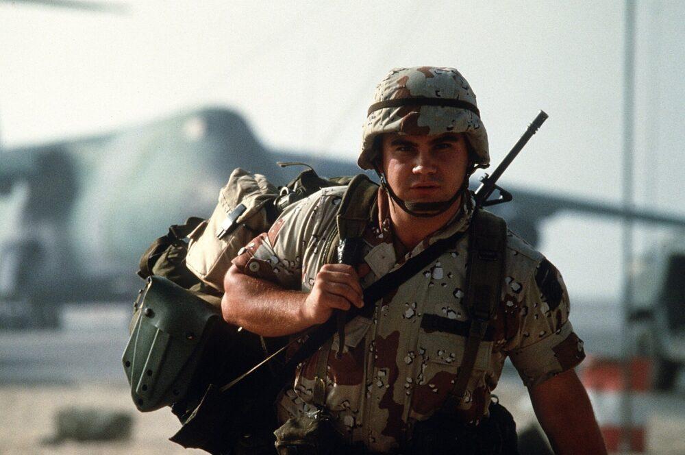 Soldier in six-colour desert camouflage uniform carrying equipment after arriving in Saudi Arabia during Operation Desert Shield.