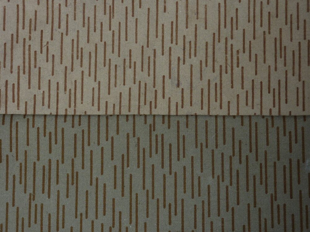 Close-up comparison of two East German Strichtarn camouflage fabric samples, an earlier printing with thinner brown dashes above a later, denser and darker printing