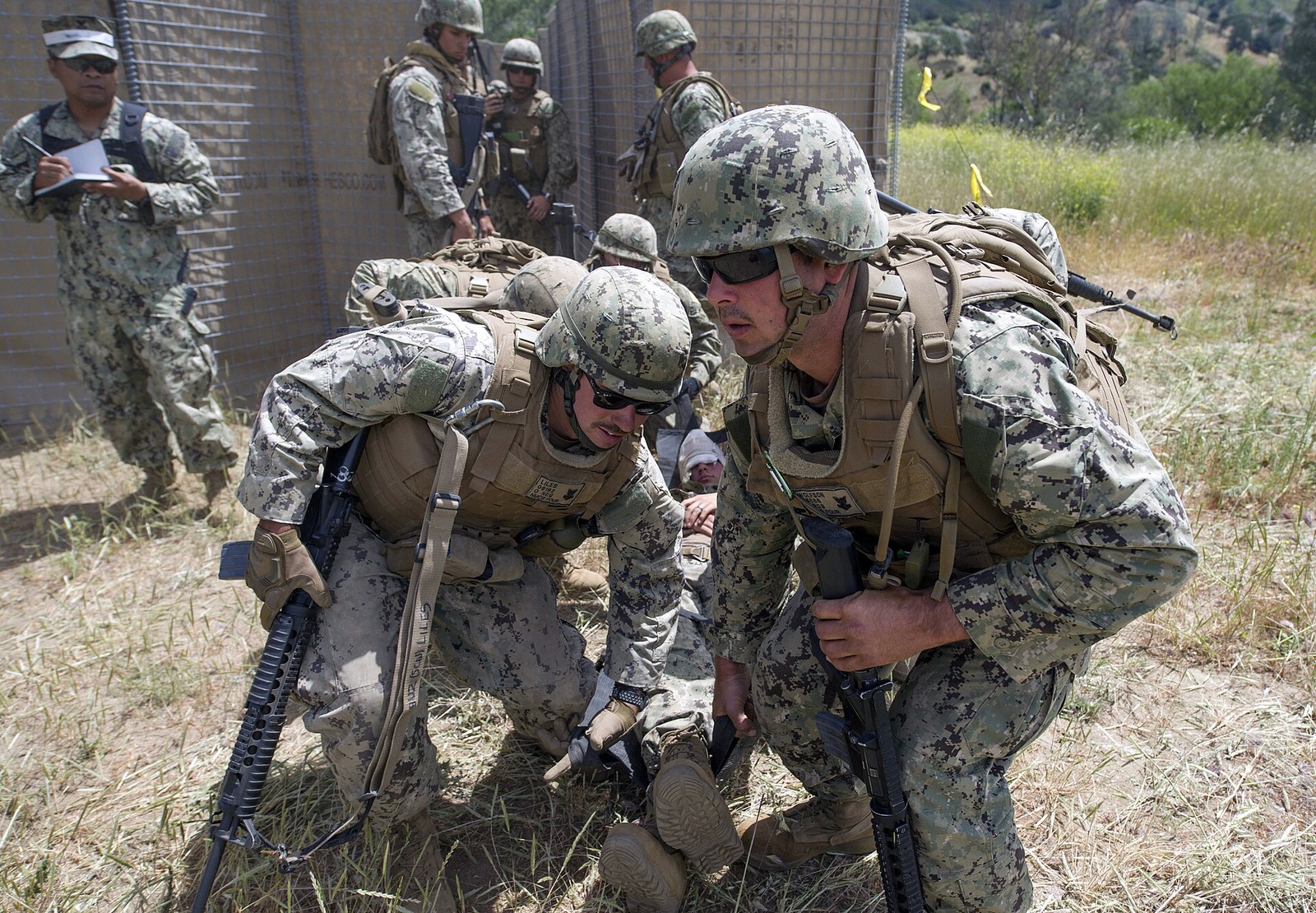 U.S. Navy Seabees in woodland digital camouflage carrying a litter during a training drill in 2017