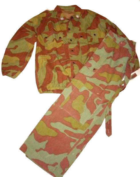 A camouflage jacket and matching trousers in pale sage green, salmon-red and ochre blotches, laid flat on a white background as a single outfit.