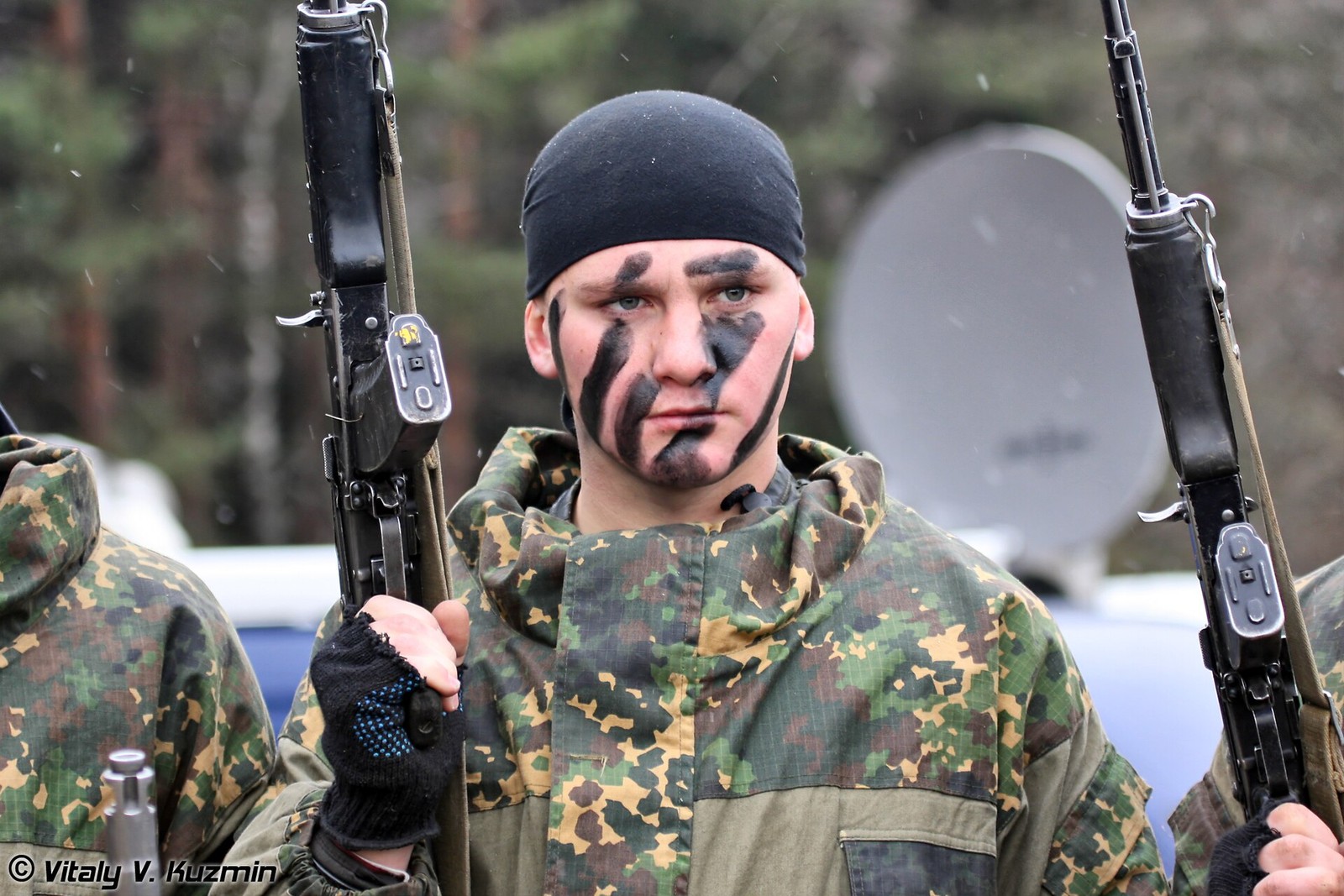 Close-up of a Russian internal troops special purpose unit serviceman with black face paint holding an assault rifle, photographed at an exhibition.