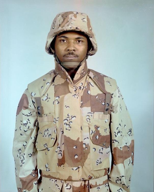Archive photograph dated February 1981 of a soldier wearing a desert camouflage fragmentation vest and a matching helmet cover over a six-colour desert-pattern uniform.