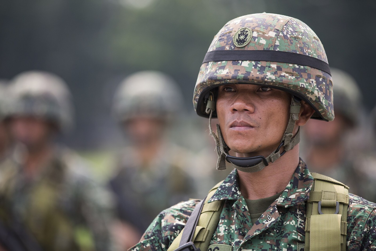 Close portrait of a Philippine Marine in formation in 2014, wearing a fine-scale green digital camouflage blouse and a matching helmet cover with a small round badge.