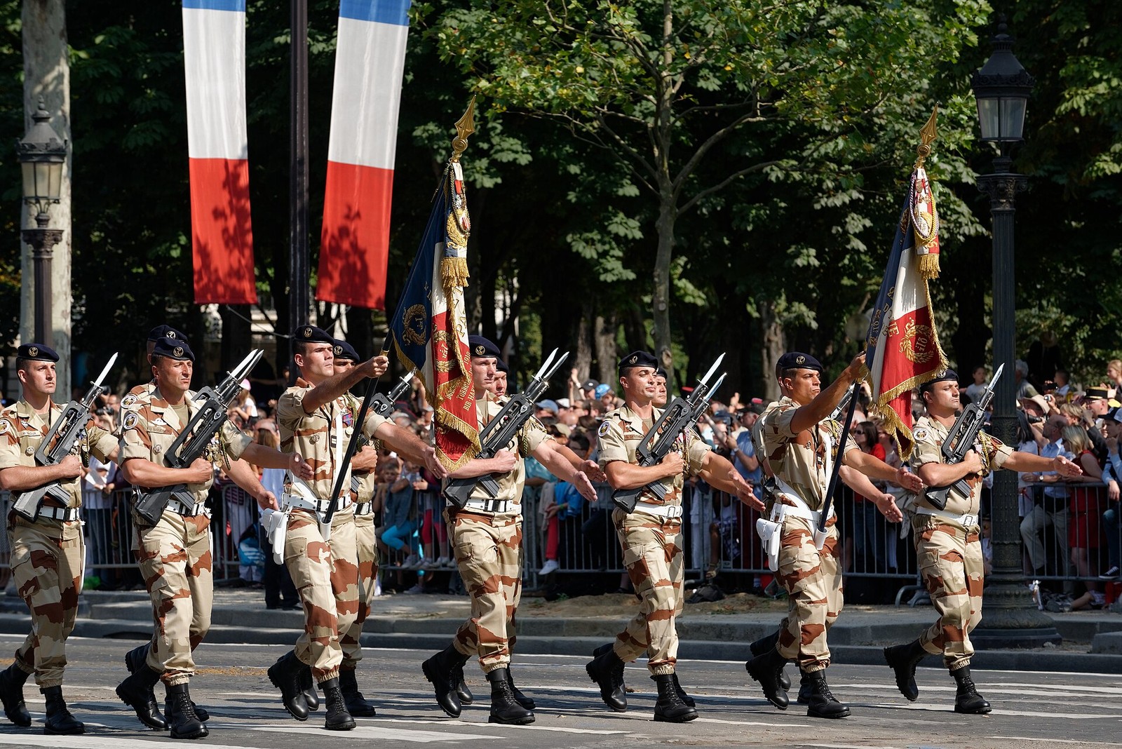 Two colour guards in desert camouflage carrying unit flags at the Bastille Day 2013 parade in Paris