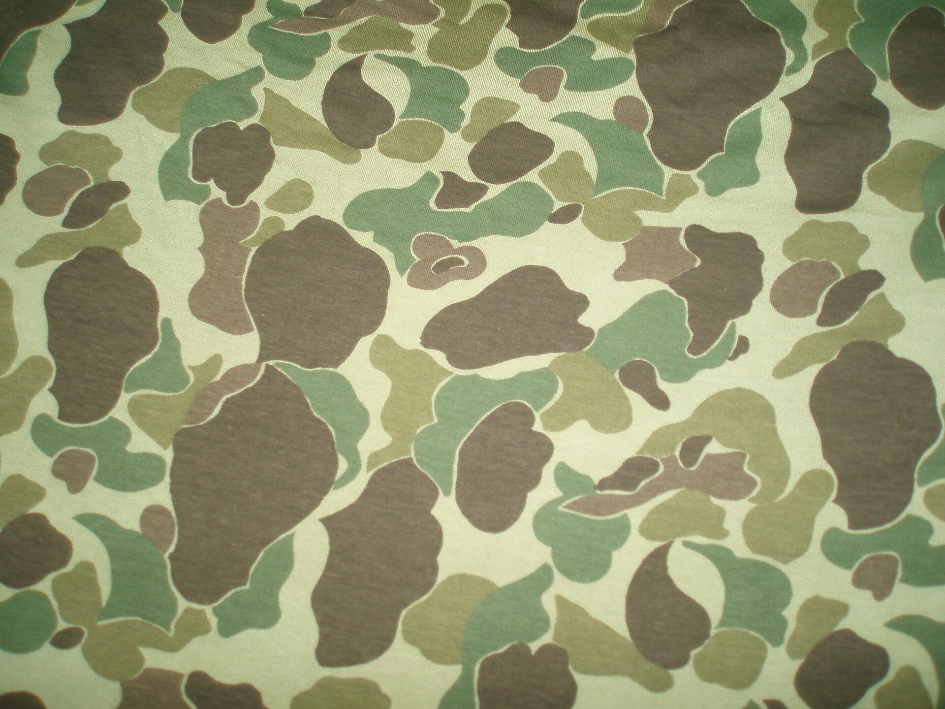 Close-up of a modern duck hunter camouflage print showing large irregular spots of dark shape on a lighter ground.