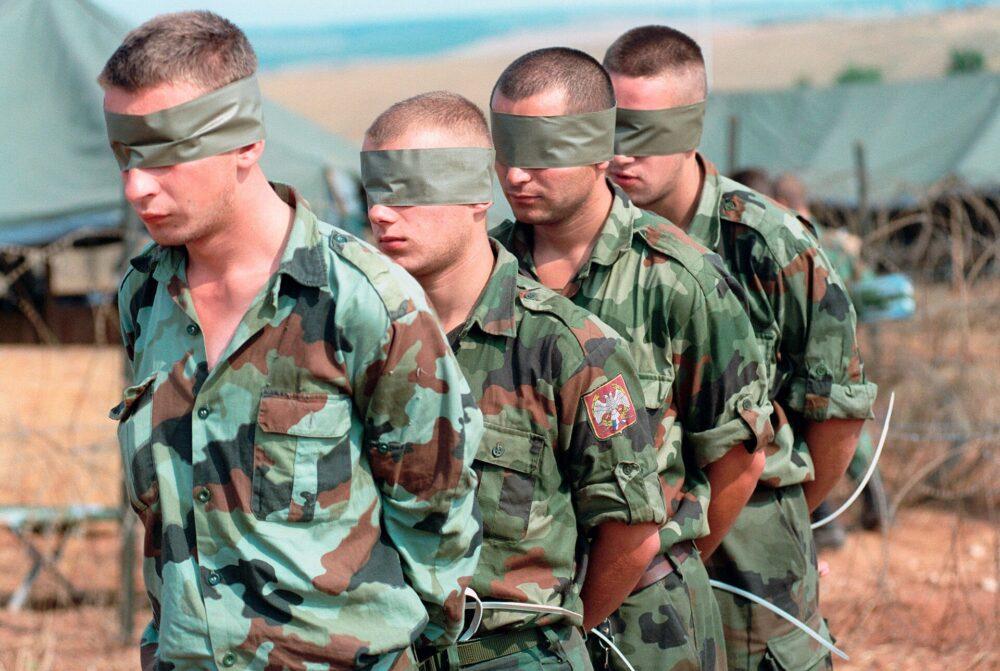 Column of Yugoslav detainees in Kosovo, July 1999, wearing bold oak-leaf pattern camouflage jackets of the Yugoslav M89 family