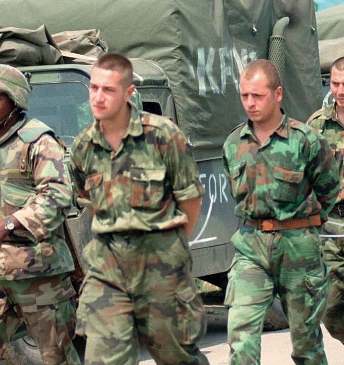 Yugoslav detainees in Kosovo in 1999 wearing large-leaf oak pattern camouflage shirts and trousers of the Yugoslav M89 family while being escorted past a military truck