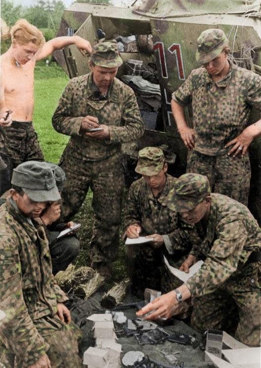 Colourised wartime photograph of soldiers of the 9th SS Panzer Division Hohenstaufen in camouflage by their Sd.Kfz.251, Normandy 1944