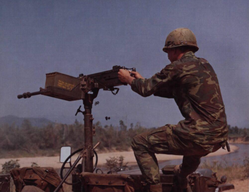 US soldier in ERDL camouflage firing a .50-calibre machine gun mounted on a jeep in Vietnam, 1969