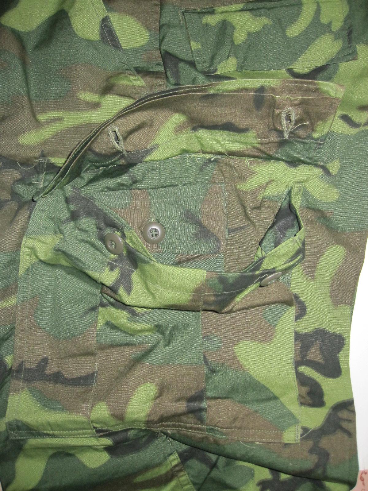 Close-up of a Vietnam-era ERDL camouflage combat trouser showing the printed leaf pattern, pocket and button