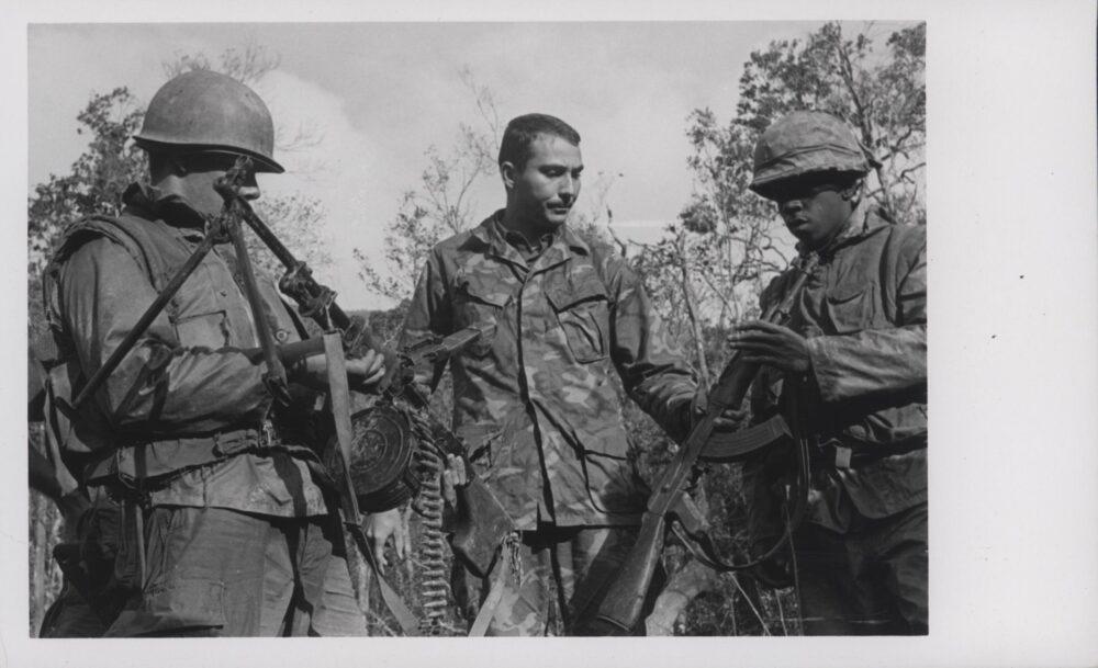 Three US Marines in ERDL camouflage examining captured weapons in Vietnam, 1969