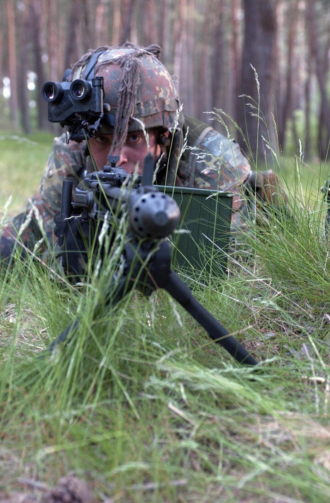 German Army soldier in Flecktarn camouflage giving covering fire during woodland assault training