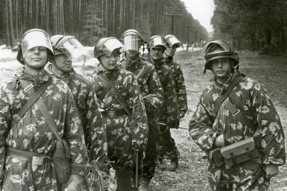 Group of Soviet soldiers in leaf camouflage standing in line at the edge of a forest