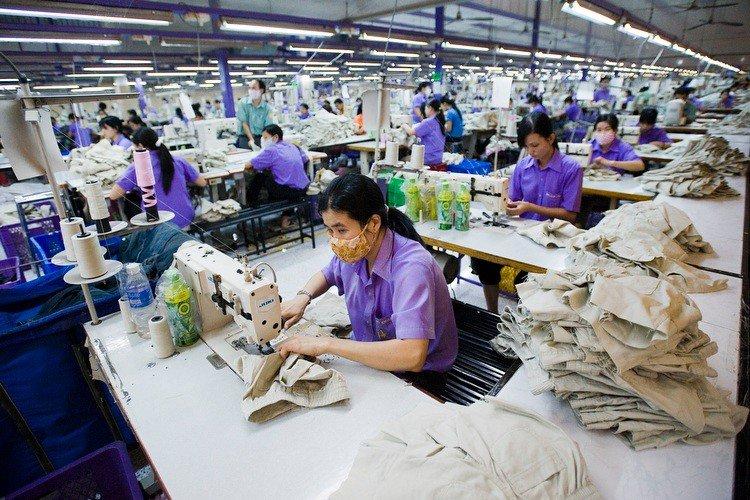 Garment workers at industrial sewing machines on a production line