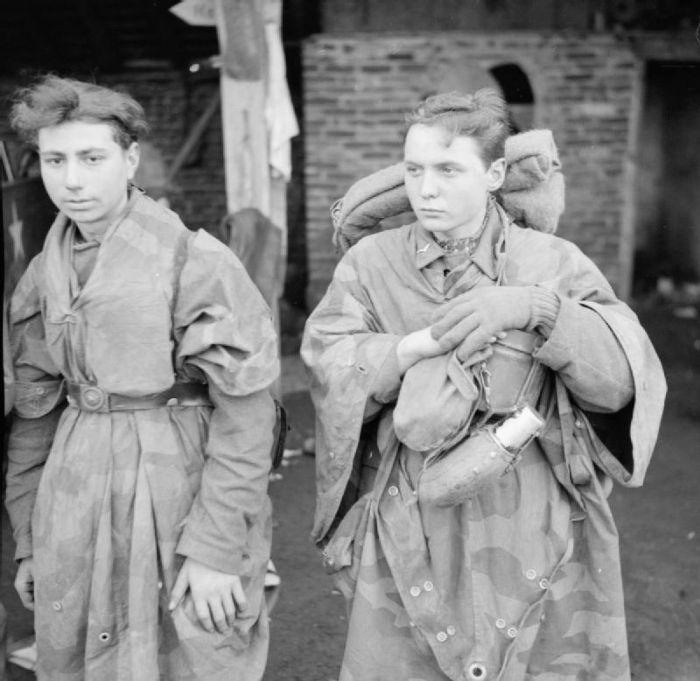 Two young German prisoners of war captured near Hamminkeln, March 1945, one wearing a shelter quarter over his uniform