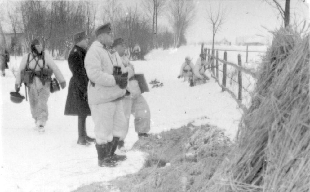 German soldiers in white winter camouflage suits walking across snow-covered ground, Russia, March 1944