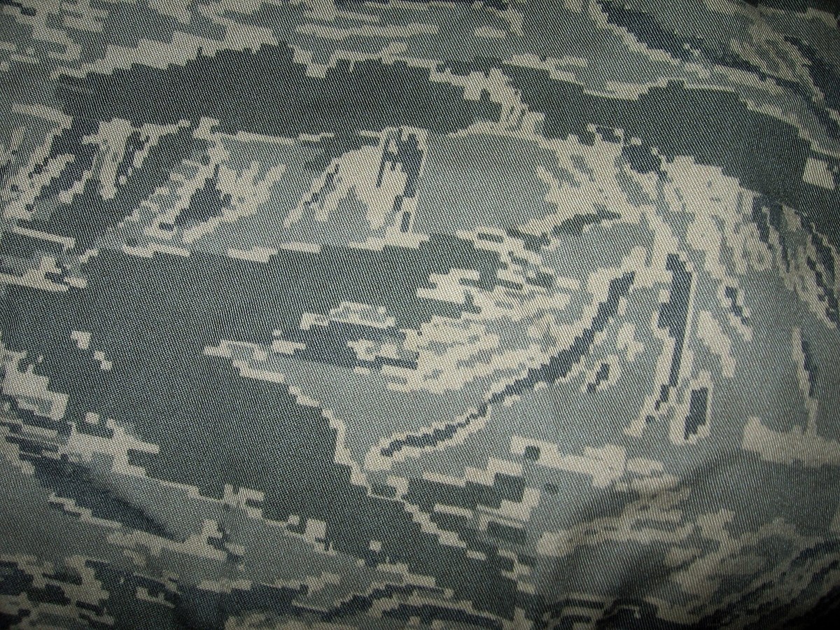 Close view of Airman Battle Uniform cloth, its digitised tiger stripe built from pale grey, slate, sage green and off-white pixels.