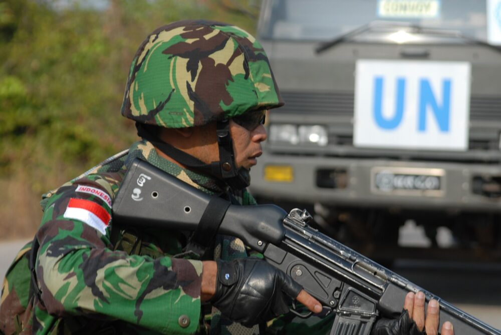 Indonesian Army infantryman wearing classic Malvinas DPM camouflage in large blocks of dark green, dark brown and cream, with a matching DPM helmet cover