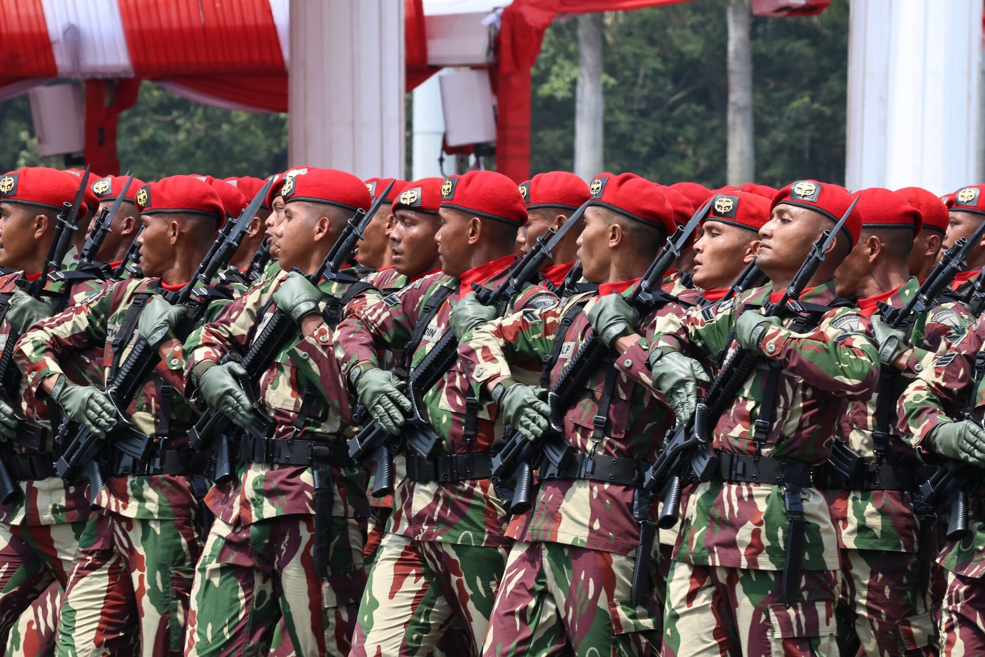 Kopassus soldiers wearing the Loreng Darah Mengalir camouflage, with vertical dark red streaks running through a green and khaki base, at the Indonesian National Armed Forces 78th anniversary parade