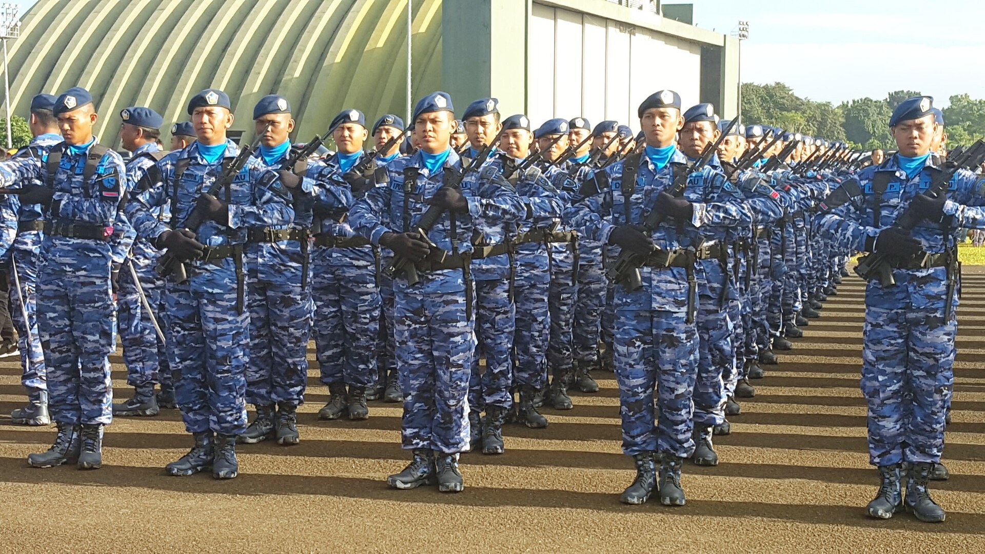 Indonesian Air Force airmen in blue and grey digital pixel camouflage during a present arms ceremony
